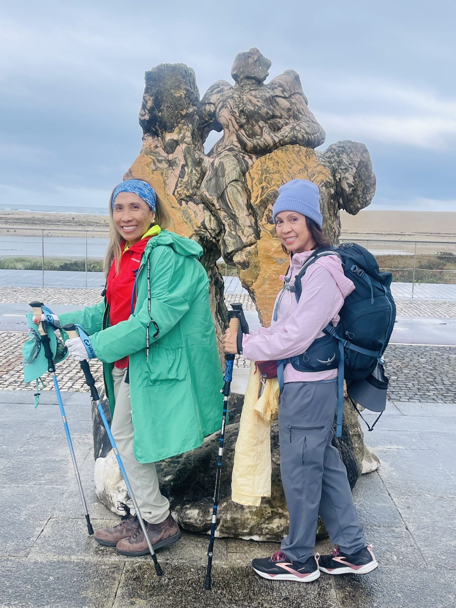 Two hikers posing by a rock sculpture.