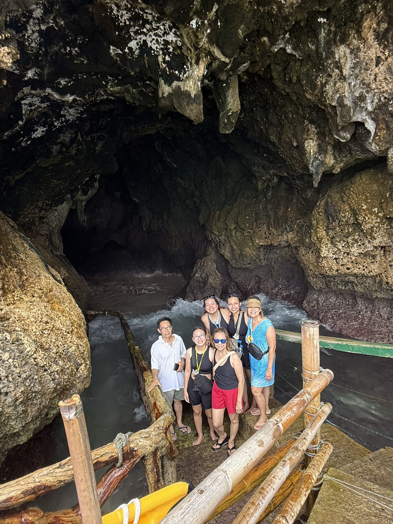 Group standing by cave entrance near water.